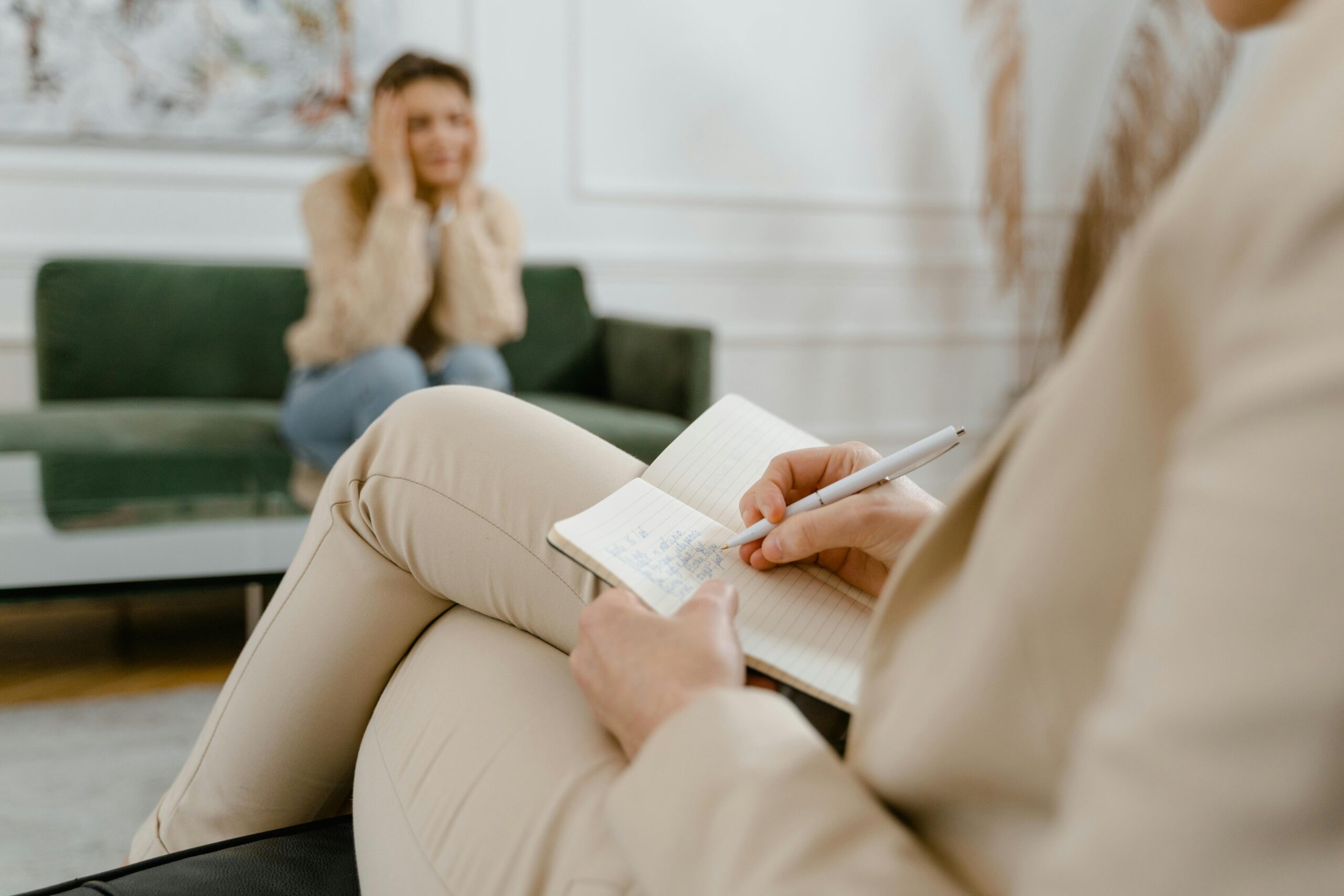 A therapist taking notes during a consultation with a patient, focusing on mental health.