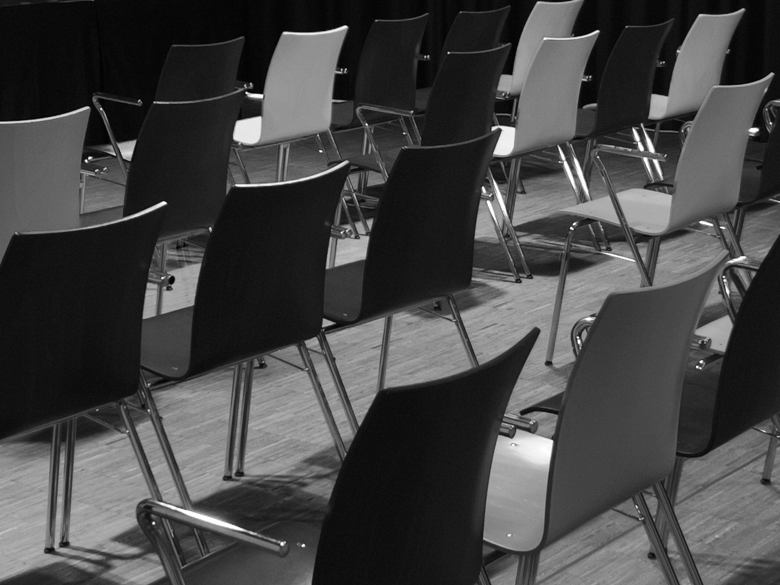 Black and white photo of empty chairs in a conference room setup.