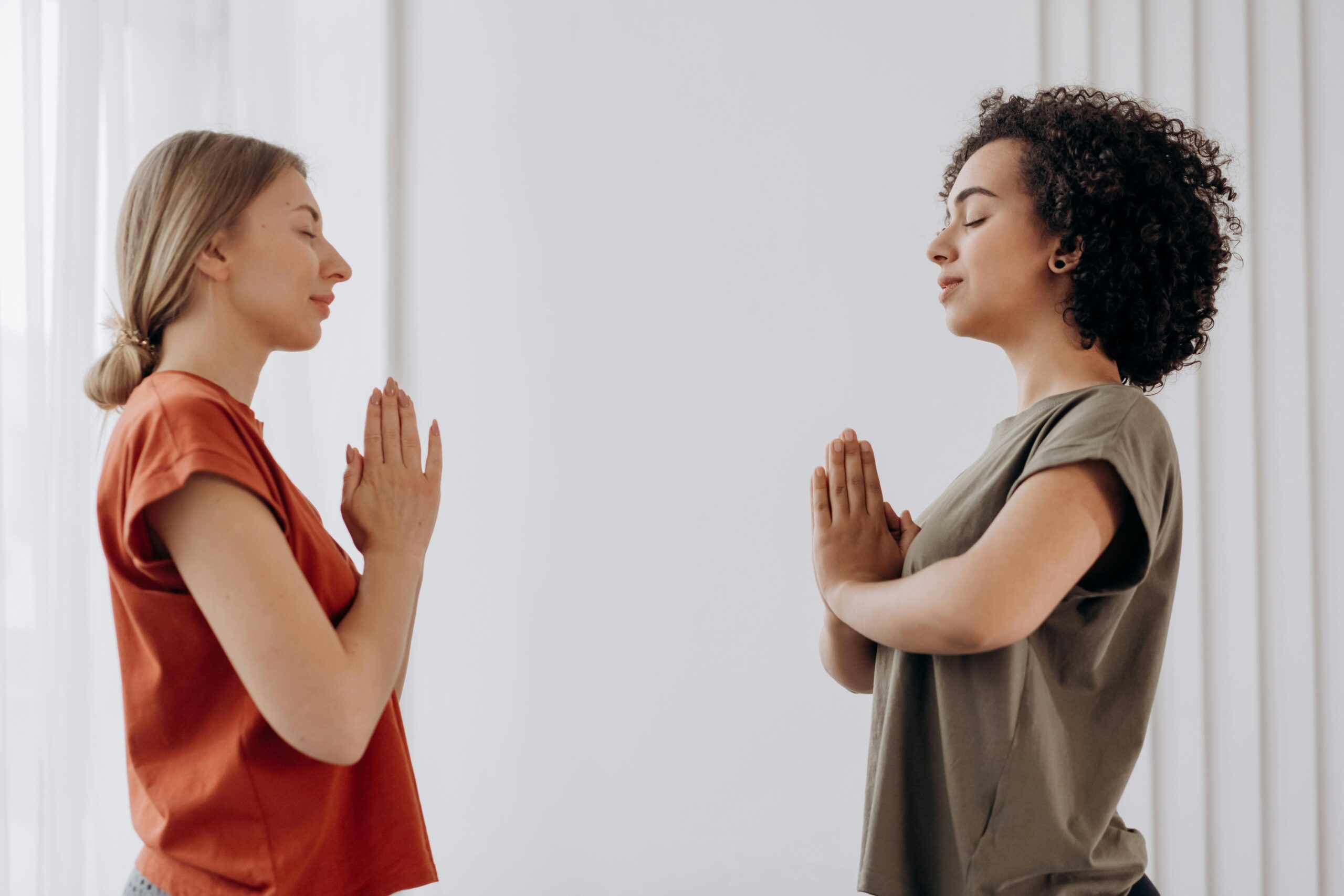 Two women practicing yoga indoors, focusing on balance and harmony.